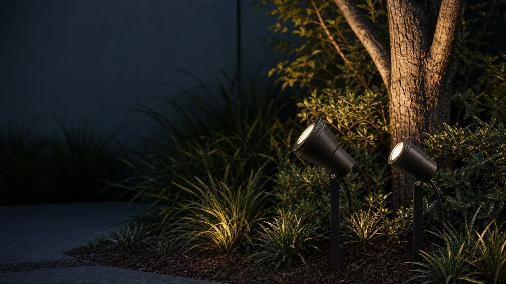 Dois espetos de jardim FlexGarden, modelos GU10 e LED, iluminando um canteiro.